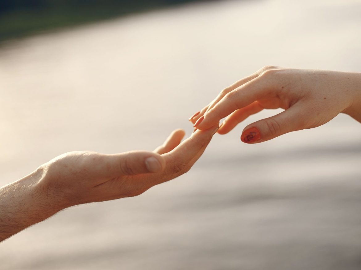 Two hands from different people reach out to each other gently